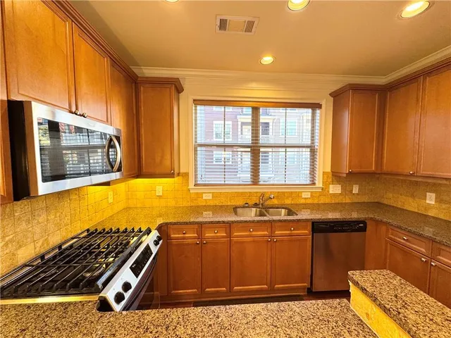 a view of a kitchen with a sink and dishwasher a oven with wooden floor