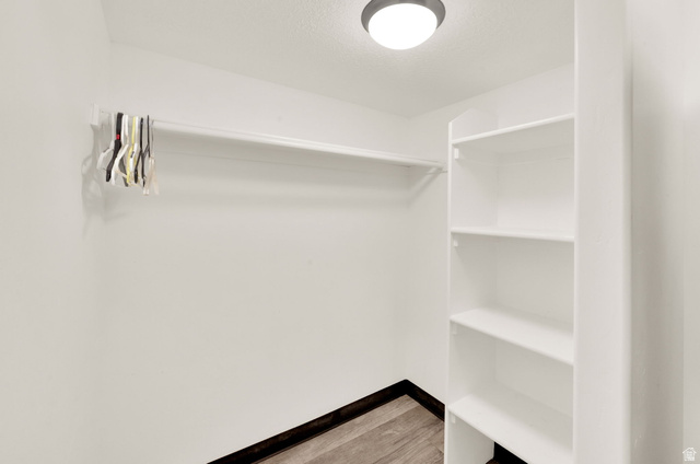 1857 Thunder Gulch Road Eagle Mountain, UT 84005 - Photo 34 of 50 Walk-in closet featuring white built-in shelving, a garment rod, recessed ceiling lighting, and wood-finish flooring