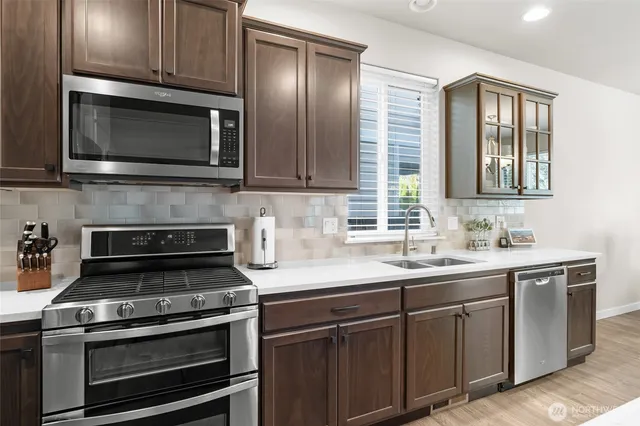a kitchen with sink a microwave a stove and cabinets