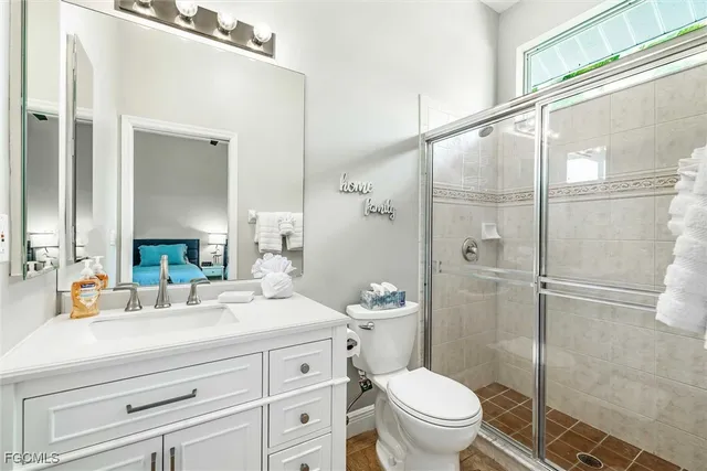 a bathroom with a toilet a sink a glass door a shower and a mirror