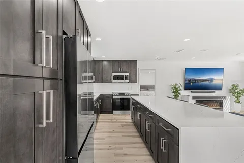 a large kitchen with stainless steel appliances a refrigerator and a stove top oven