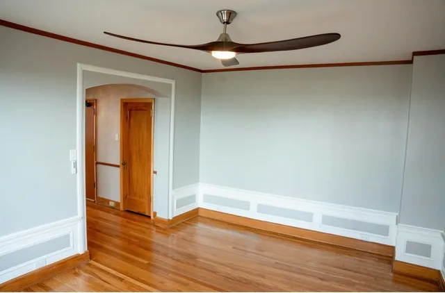 a view of empty room with wooden floor and fan