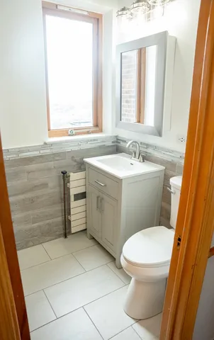 a bathroom with a sink a toilet a window and vanity