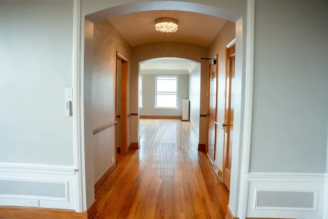 a view of a hallway with wooden floor and a living room