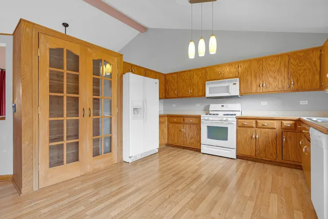 a kitchen with granite countertop wooden floors stainless steel appliances and sink