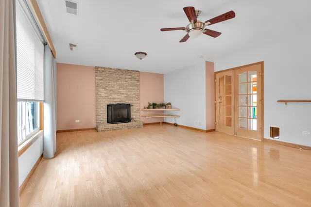 a view of a livingroom with a fireplace a ceiling fan and wooden floor