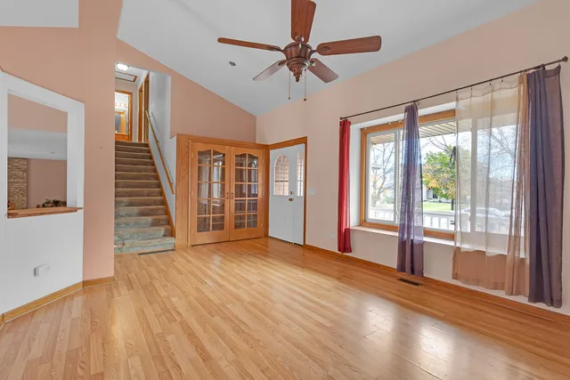 a view of an empty room with wooden floor and a window