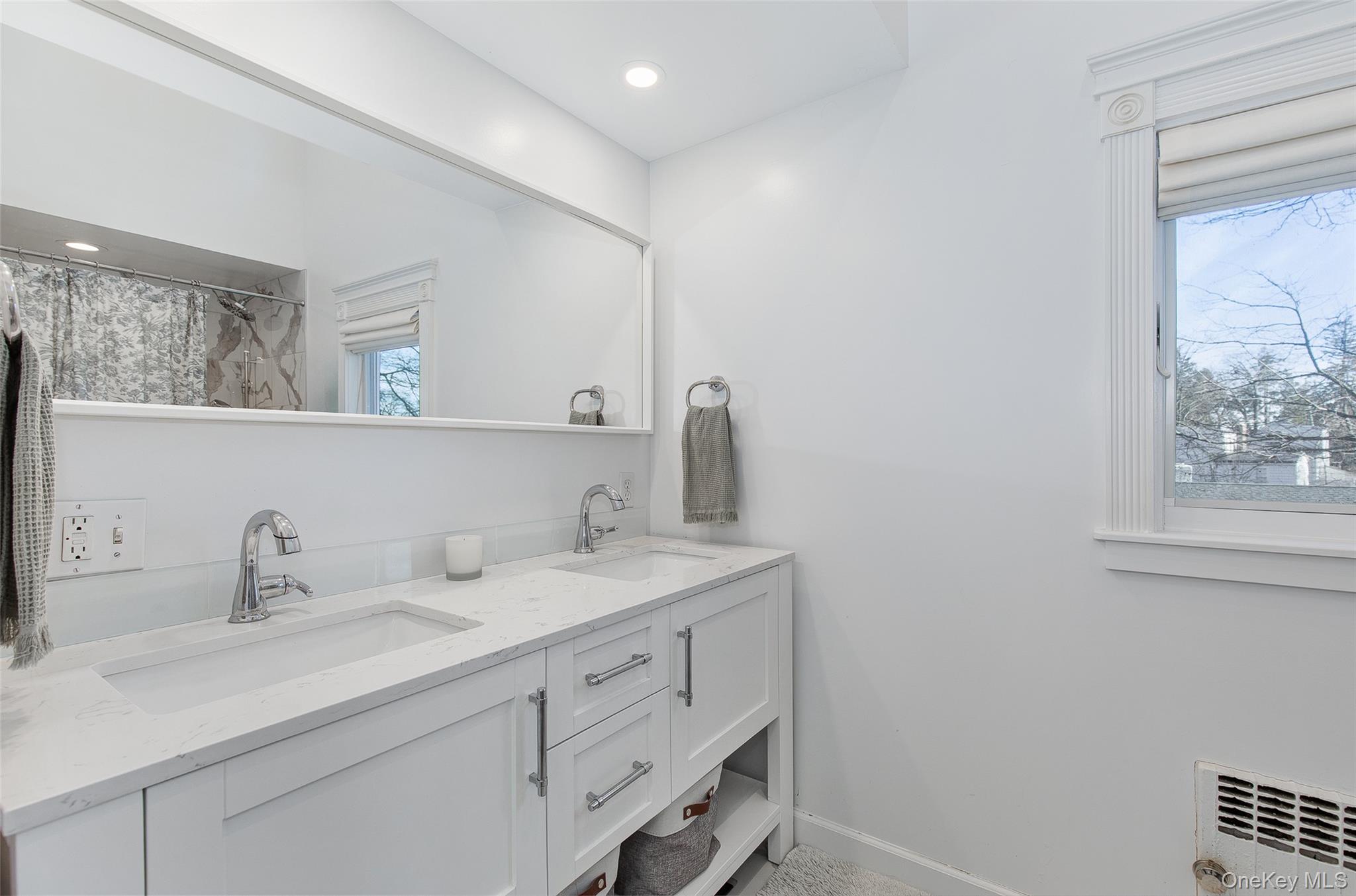 25 Roxbury Road Scarsdale, NY 10583 - Photo 17 of 32 The renovated, spa-style ensuite primary bathroom features two sinks, a high vaulted ceiling, soaking tub, and shower.