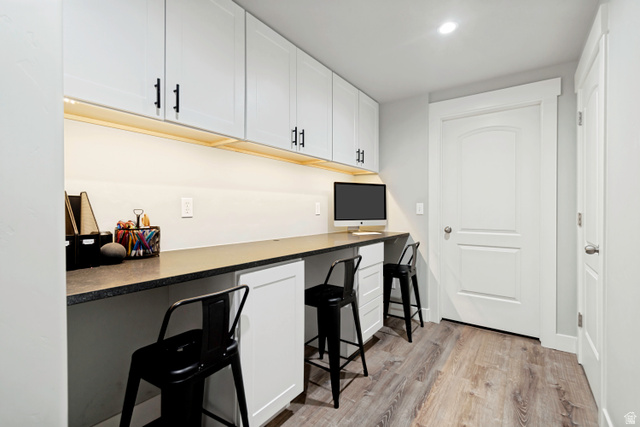 983 West 1550th Street South Springville, UT 84663 - Photo 33 of 43 Dedicated workspace featuring light wood-finish flooring, an extended countertop, under-cabinet lighting, multiple white upper cabinets with matte black hardware, and two white lower cabinets.