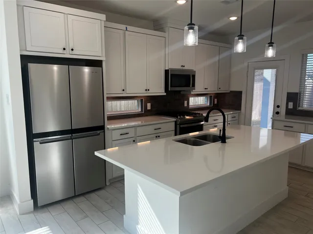 a kitchen with stainless steel appliances a sink a stove a microwave a center island and wooden floor