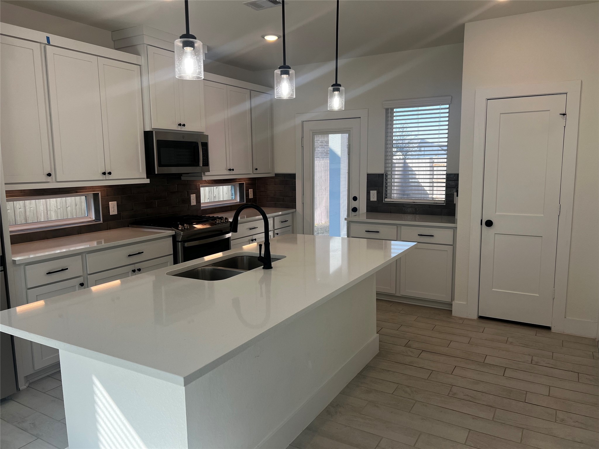 7743 Swooping Swallow Lane Katy, TX 77493 - Photo 15 of 45 a kitchen with stainless steel appliances a sink a stove a microwave a center island and wooden floor