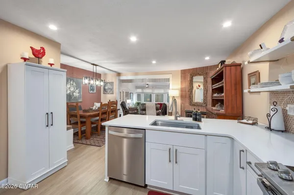 a kitchen that has a sink and a stove with wooden floors