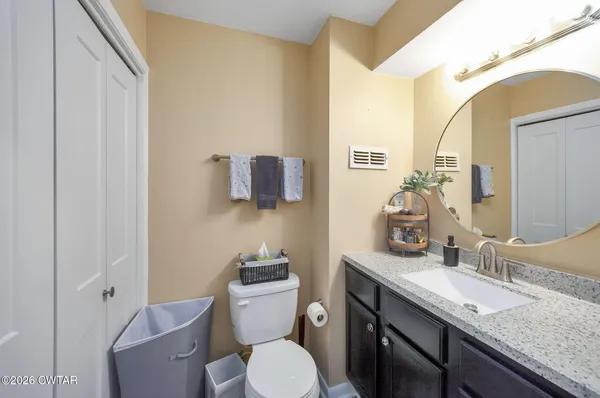 a bathroom with a granite countertop toilet sink and mirror