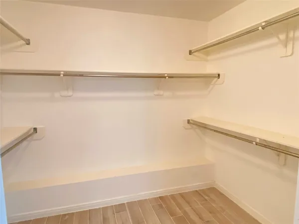 a view of walk in closet with empty racks
