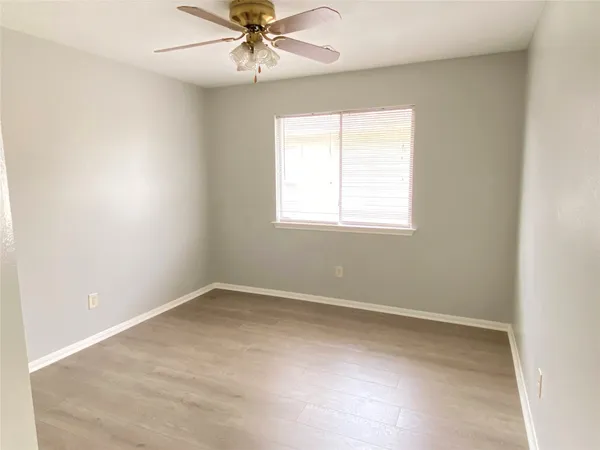 an empty room with a window and a fan