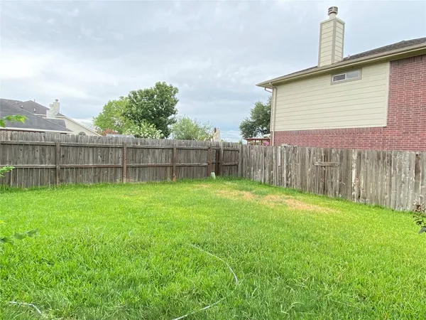 a view of a backyard with a garden and wooden fence