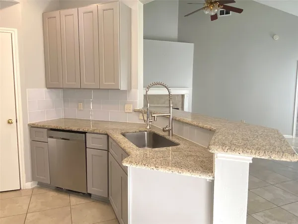 a kitchen with granite countertop a sink a stove and cabinets