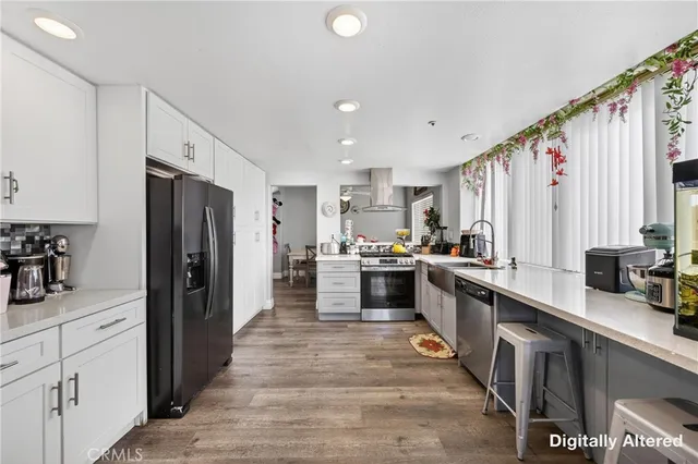 a large kitchen with stainless steel appliances a refrigerator a sink a stove and cabinets