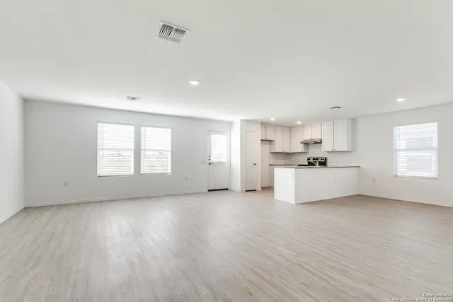 a view of a kitchen with a sink wooden cabinets and a window