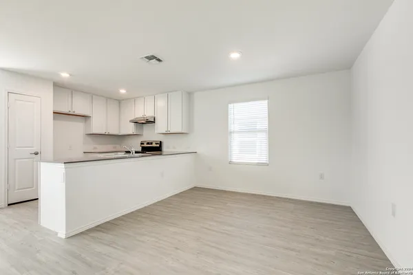 a kitchen with granite countertop white cabinets and wooden floor