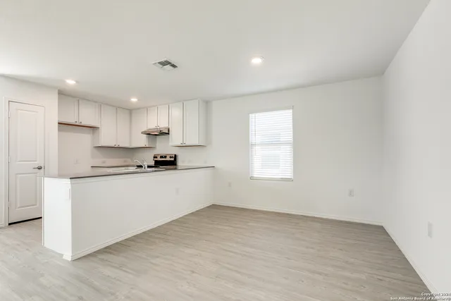 a kitchen with granite countertop white cabinets and wooden floor