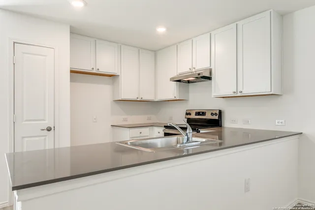 a kitchen with stainless steel appliances granite countertop a sink and a white cabinets