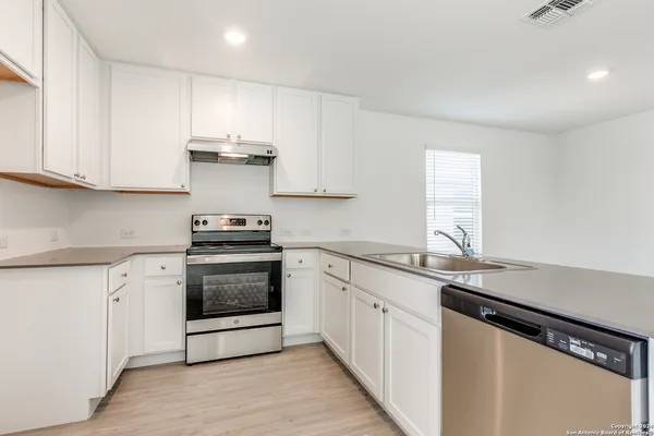 a kitchen with granite countertop white cabinets and appliances