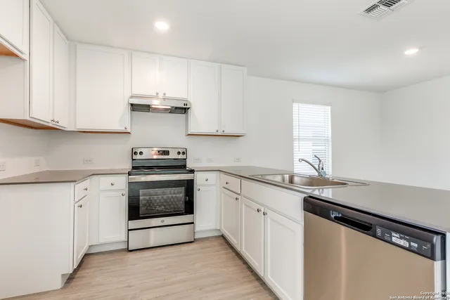 a kitchen with granite countertop white cabinets and appliances