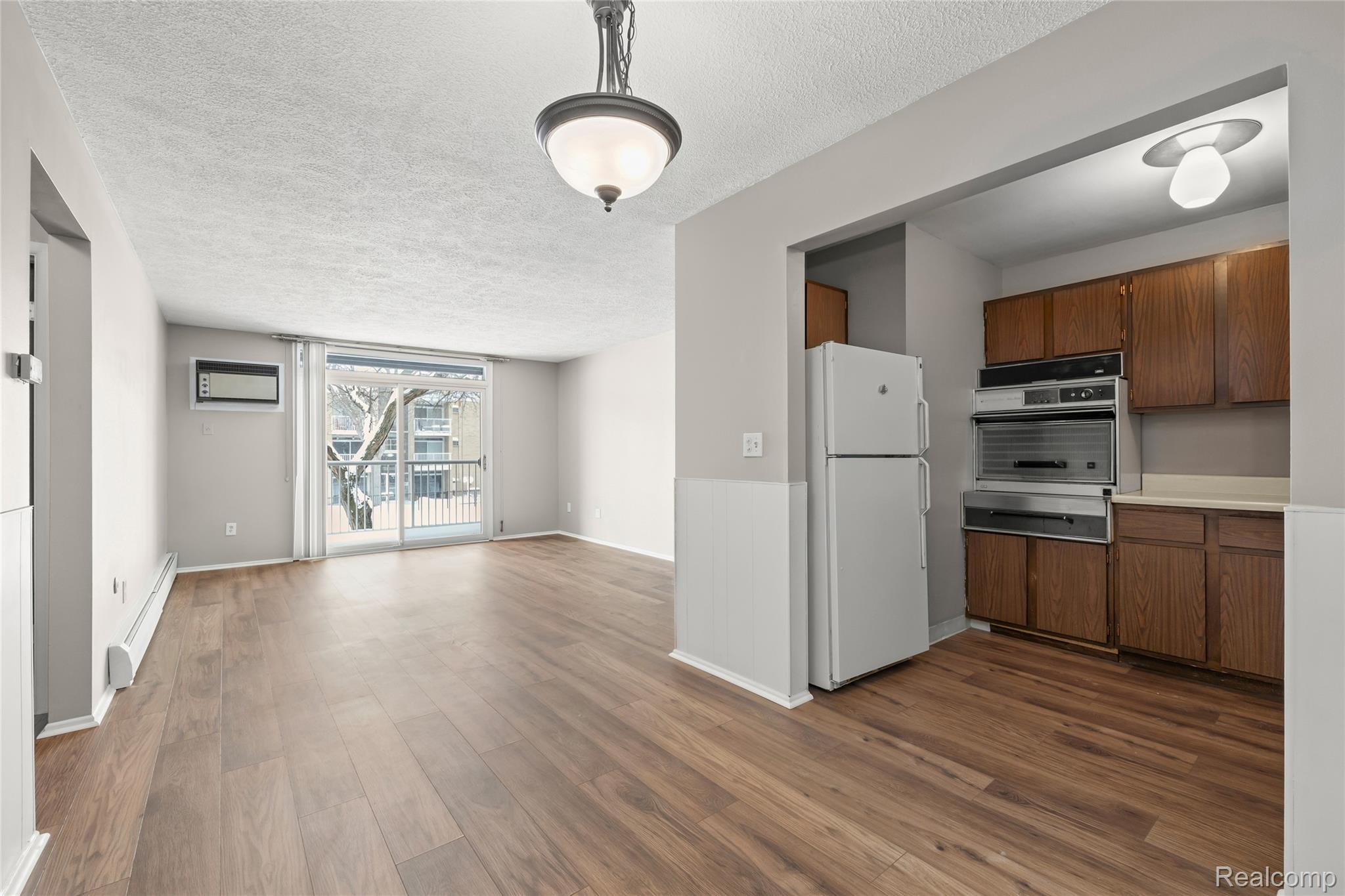 4909 Crooks Road, Unit D6 Royal Oak, MI 48073 - Photo 10 of 16 Kitchen with light countertops, freestanding refrigerator, a textured ceiling, new wood-style flooring, and decorative light fixtures