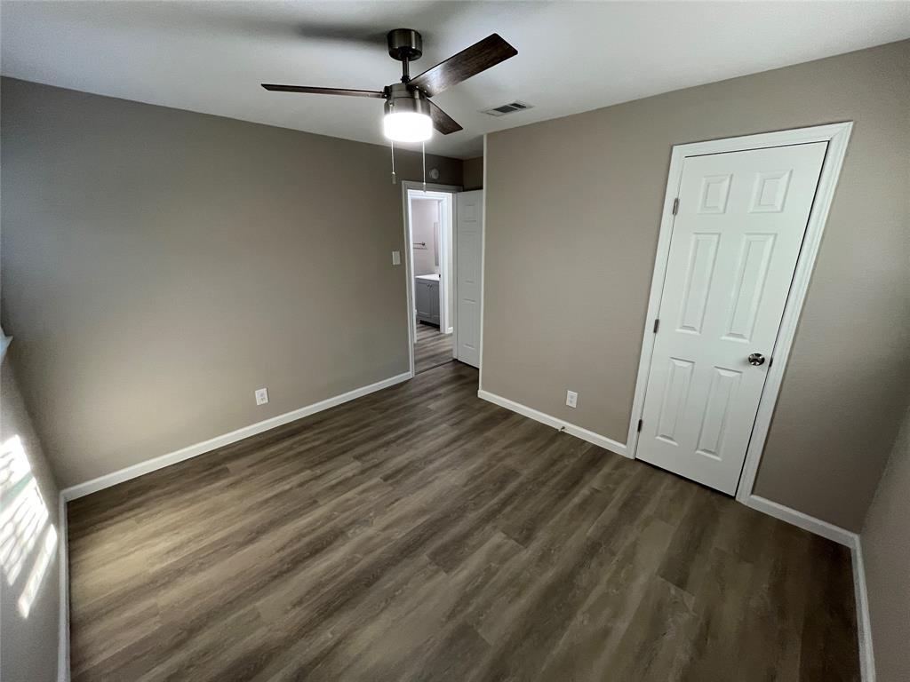 207 Wilmer Heights Drive Wilmer, TX 75172 - Photo 18 of 22 an empty room with wooden floor fan and windows
