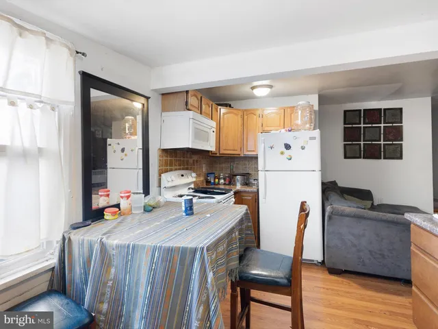 a kitchen that has a refrigerator a stove a dining table and chairs with wooden floor