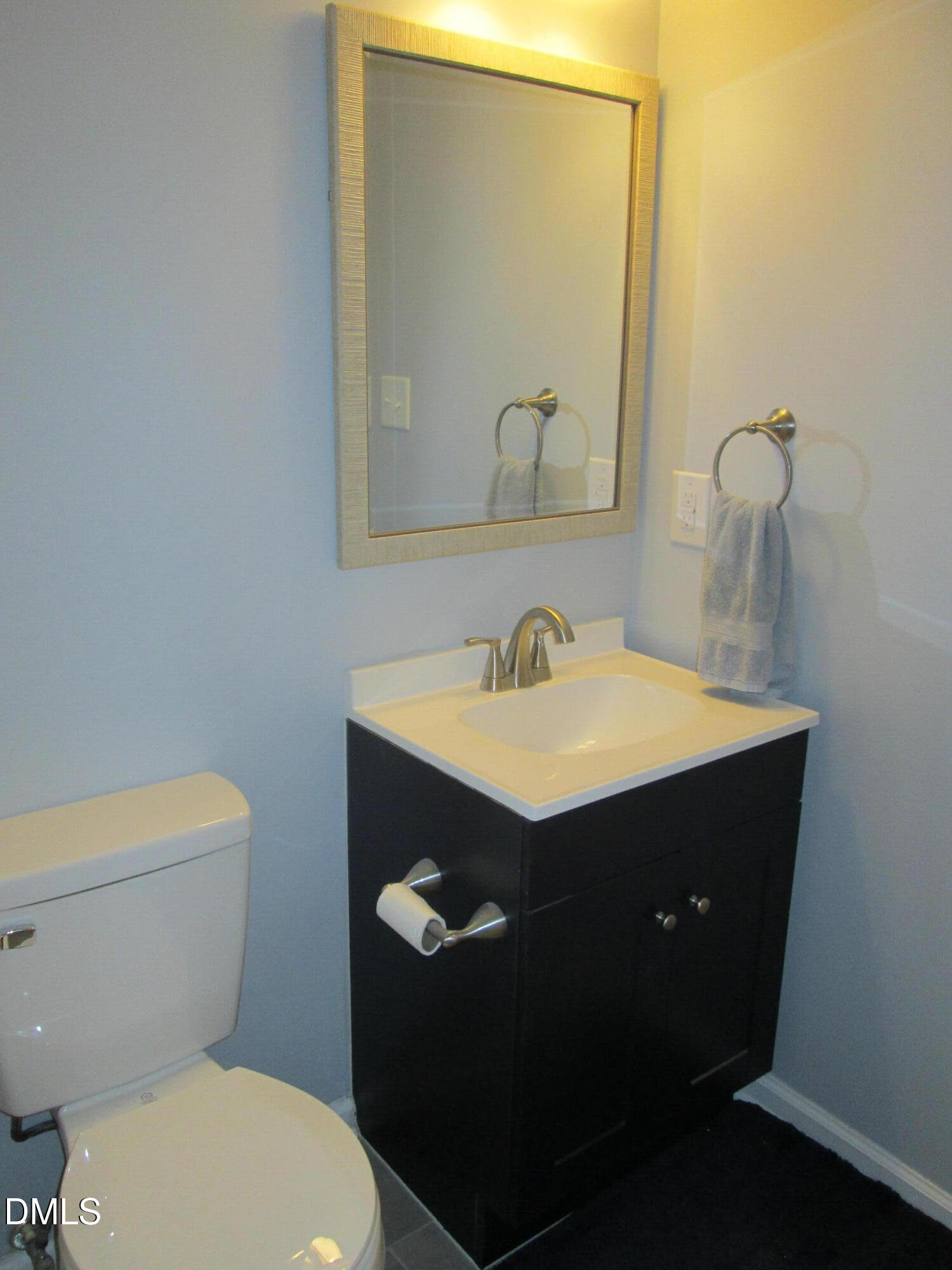 4651 Timbermill Court, Unit 103 Raleigh, NC 27612 - Photo 30 of 40 Vanity with a white integrated sink, dark wood-finish cabinetry, and a framed mirror