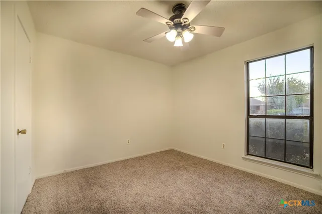 an empty room with a ceiling fan and a window