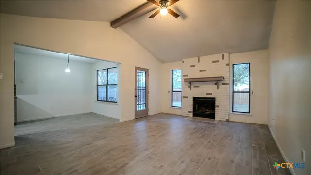 an empty room with windows fireplace and wooden floor