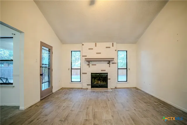 an empty room with fireplace and wooden floor