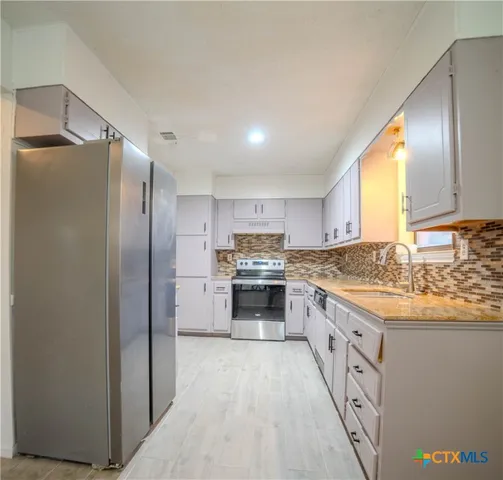 a modern kitchen with stainless steel appliances granite countertop a stove and a refrigerator