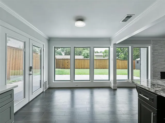 an empty room with wooden floor and windows with curtains