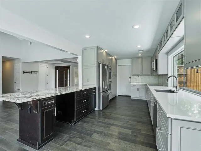 a large kitchen with stainless steel appliances granite countertop a lot of counter space and wooden floor