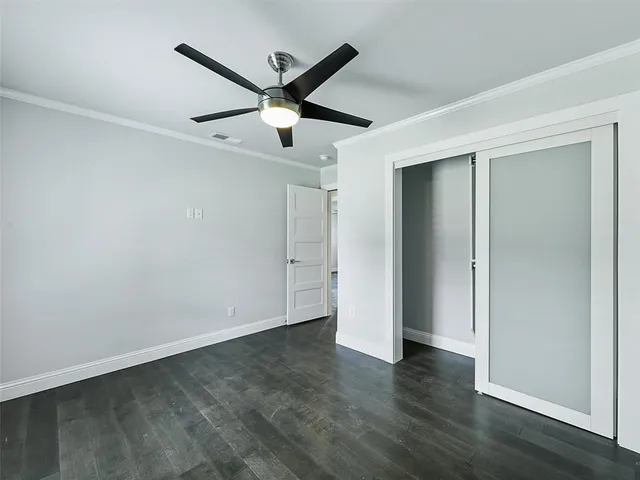 an empty room with wooden floor and a ceiling fan