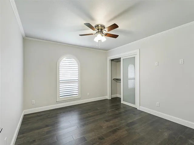 an empty room with wooden floor chandelier fan and windows