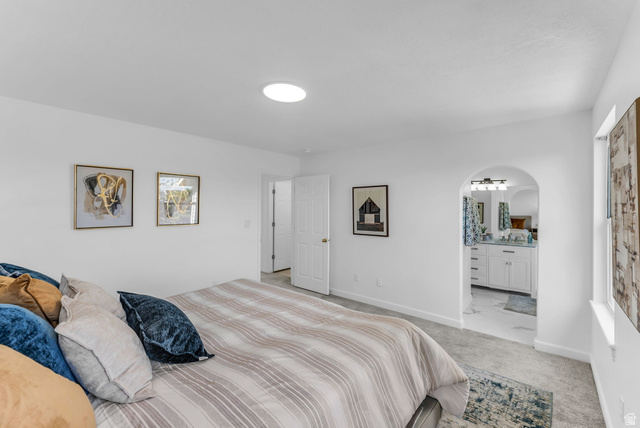 1147 West State Road Lehi, UT 84043 - Photo 18 of 31 Spacious bedroom featuring light gray carpet, recessed lighting, and a broad arched entryway leading to a bathroom with a double vanity