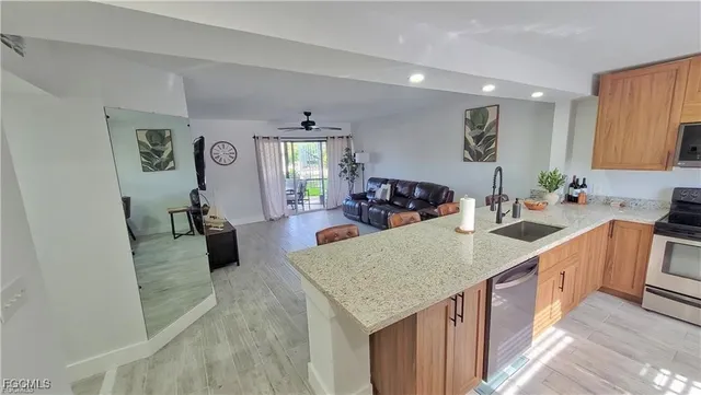 a kitchen with a stove a sink a refrigerator and blue cabinets with wooden floor