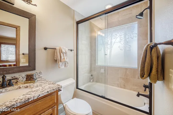 a bathroom with a granite countertop sink toilet and shower