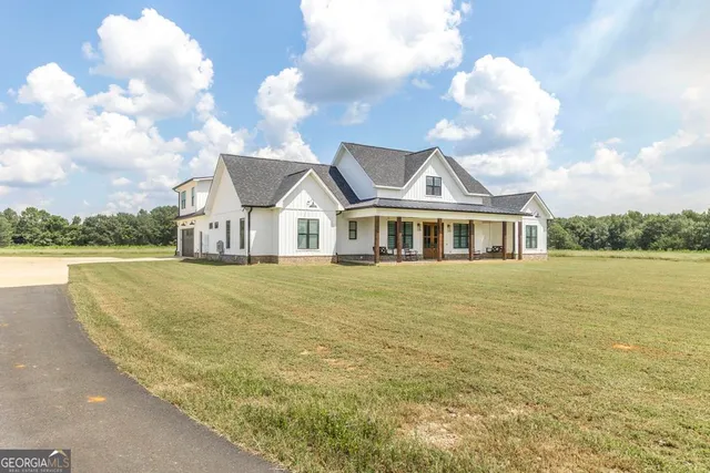 a view of a white house with a swimming pool and a yard