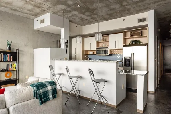 a kitchen with stainless steel appliances kitchen island granite countertop a refrigerator and microwave