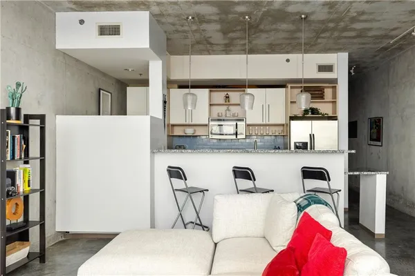 a living room with stainless steel appliances furniture and a book shelf