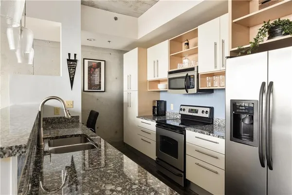 a kitchen with stainless steel appliances granite countertop a stove a sink and a refrigerator
