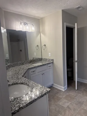 a bathroom with a granite countertop sink and a mirror