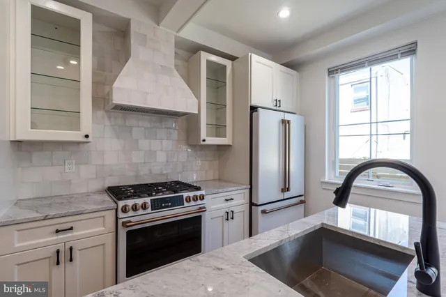 a kitchen with granite countertop a stove a sink and a refrigerator