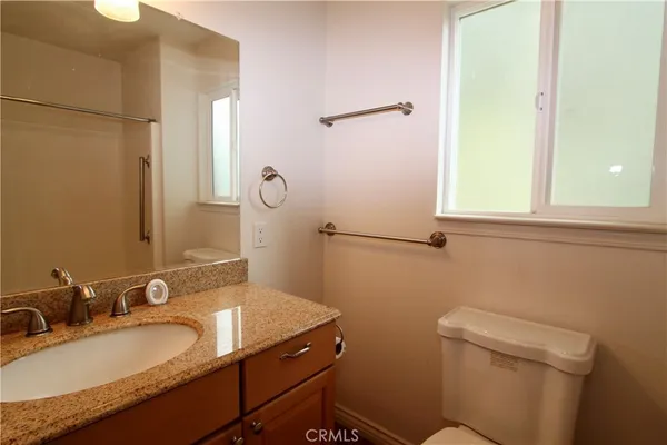 a bathroom with a granite countertop sink toilet and mirror